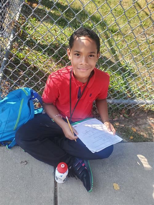  sCaleb Howard being relentless and responsible by doing his homework while waiting on the bus.